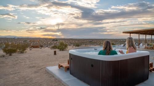 two women sitting in a hot tub in the desert at Loma Vista By The Cohost Company in Sunfair Heights