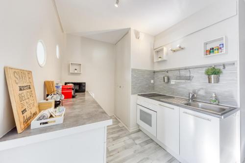 une cuisine avec des armoires blanches et un évier dans l'établissement Grand studio proche Disney / Val d'Europe, à Lagny-sur-Marne