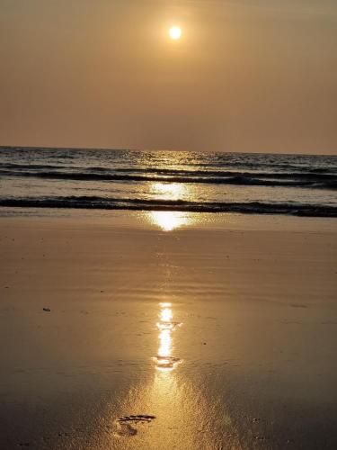 a sunset on a beach with the ocean at Luxury Konkan Beach Stay Guhagar in Guhagar