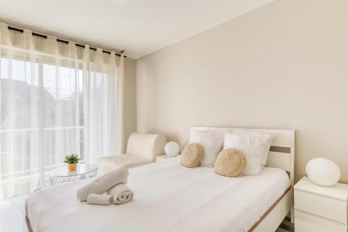 a white bedroom with a bed and a chair at Grand studio proche Disney / Val d'Europe in Lagny