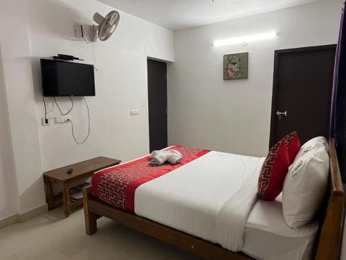 a bedroom with a bed and a tv on the wall at BanyanThree in Kodaikānāl