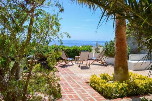a patio with chairs and the ocean in the background at Maridea - Cave Apartments in Ponza