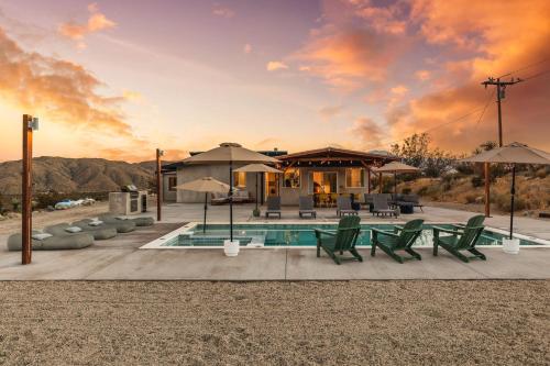 a house with a pool and chairs and umbrellas at Hotel California By The Cohost Company in Morongo Valley