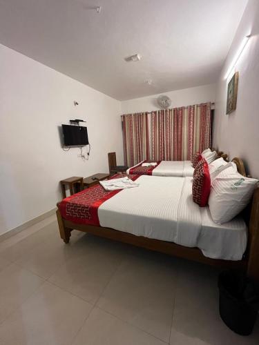 a bedroom with a large bed with red and white pillows at BanyanThree in Kodaikānāl