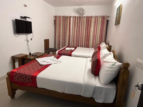 a bedroom with two beds with red and white sheets at BanyanThree in Kodaikānāl
