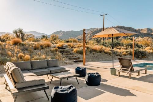 a patio with a couch and chairs and an umbrella at Hotel California By The Cohost Company in Morongo Valley