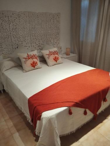 a bedroom with a white bed with a red blanket at azahar playa apartmento in Mazarrón