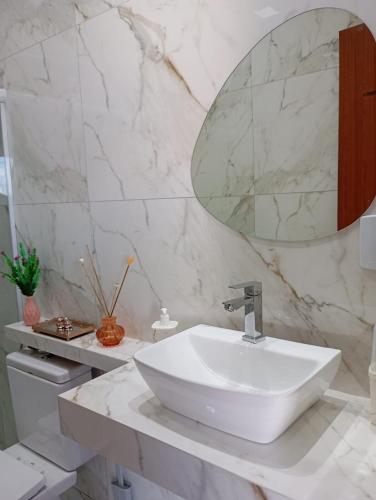 a white bathroom with a sink and a mirror at Casa confortável in Arembepe in Camaçari