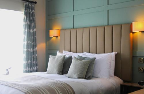 a bedroom with a large bed with white pillows at Coach & Horses Dersingham in Dersingham