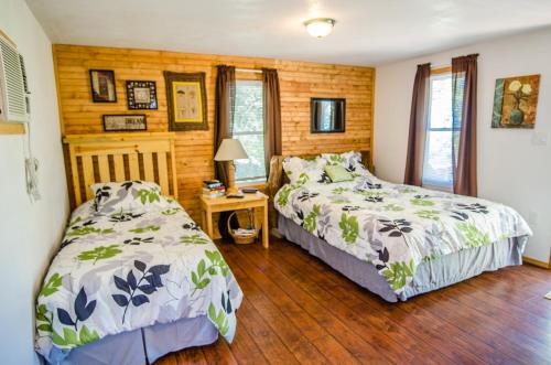 two beds in a bedroom with wooden walls at Whispering Woods Cabins & Grill in Jordan