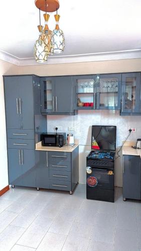 a kitchen with blue cabinets and a microwave at Spacious 2Bedroom Apartment Muyenga-Bukasa in Kampala