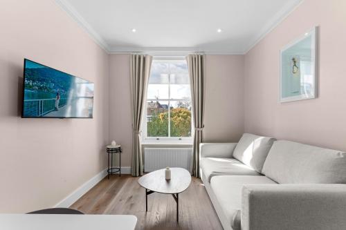 a white living room with a couch and a table at Grove Heights Notting Hill in London