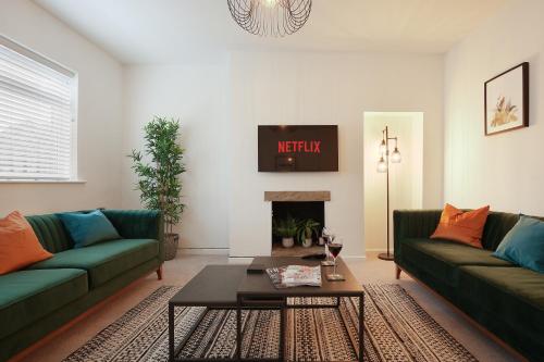 a living room with two green couches and a fireplace at The Lodge - comfortable, stylish, 3 bedroom home with 3-6 beds near Utilita Arena - free parking in Sheffield