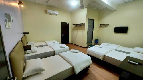a room with four beds in a room with a tv at Hotel Bestari in Melaka