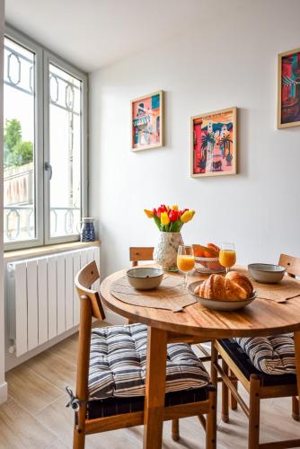 une salle à manger avec une table et des chaises en bois dans l'établissement Le Jardin de Frida by CozyLife - Cœur de Ville, à Niort