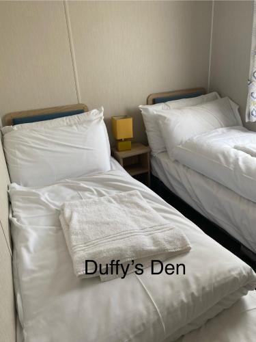 two beds sitting next to each other in a room at Duffy's Den - Parkdean California Cliffs - Fulmar 45 in Scratby