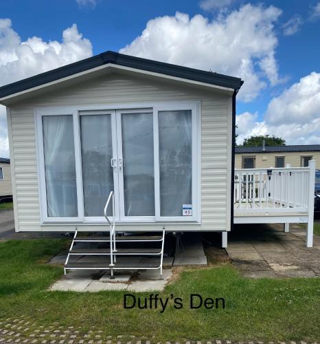 a tiny house with a large window and a porch at Duffy's Den - Parkdean California Cliffs - Fulmar 45 in Scratby
