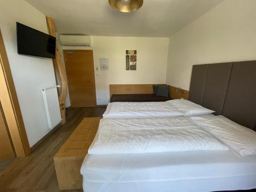two twin beds in a room with a tv at Guesthouse Dolomiten in Egna