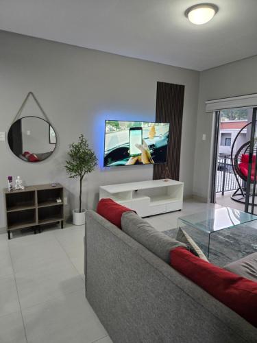 a living room with a couch and a tv on the wall at iThusi-CBD in Mbabane