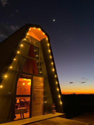 Un petit bâtiment avec des lumières allumées la nuit dans l'établissement Cabana Vila Suíça, à Pedro II