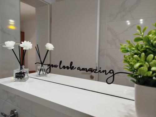 a bathroom sink with a mirror and flowers on it at Anna Maris apartment in Rab
