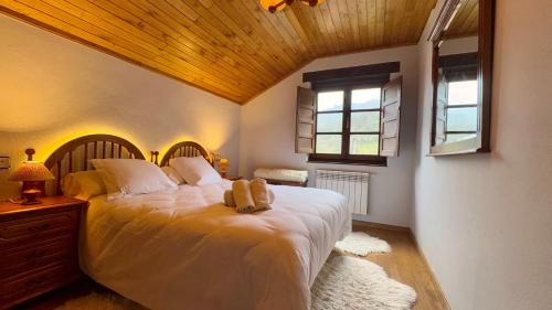 1 dormitorio con 1 cama blanca grande y techo de madera en Apartamentos y Casas de Aldea La Pornacal, en Villar de Vildas