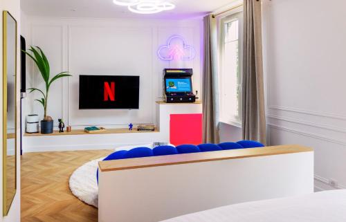 a living room with a tv and a blue couch at Le Nuage - Hypercentre - Luxe Suite Spa & Gaming in Troyes