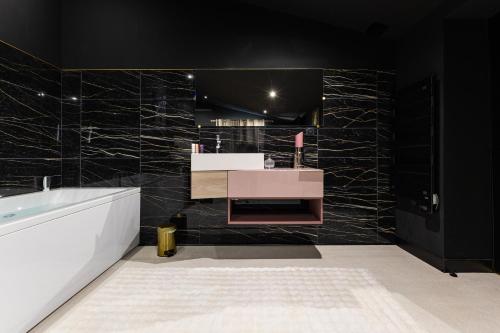 a bathroom with a sink and a tub and black walls at SecretRoom - Luxe, Balnéo et évasion -Arnage in Arnage