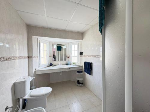 a bathroom with a toilet and a sink and a mirror at Villa Sofía - 2 bedroom villa with private pool and garden in Baños y Mendigo