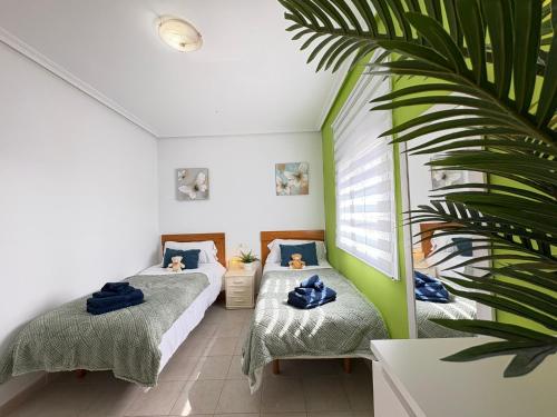 two beds in a room with a palm tree at Villa Sofía - 2 bedroom villa with private pool and garden in Baños y Mendigo