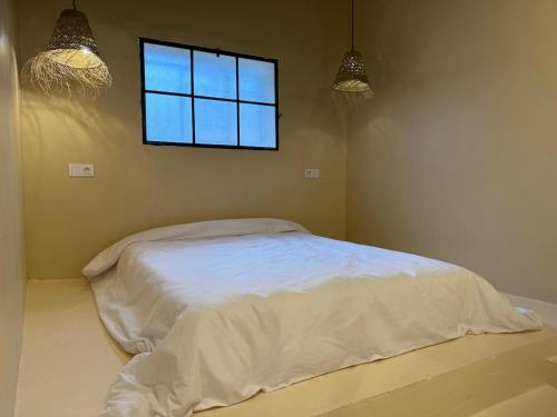 a bedroom with a white bed with a window at Simple Moroccan Rural Getaway in Tama ou Ennza