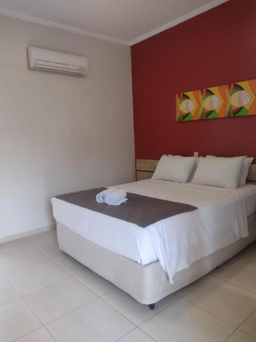 a bedroom with a large white bed in a room at Hotel Rosa da Ilha Guaruja - Perto do Mar com piscina in Guarujá