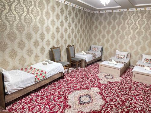 a room with three beds and a red carpet at Madina-Mehribon in Bukhara