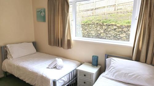 zwei Einzelbetten in einem Zimmer mit Fenster in der Unterkunft Sand Bay, Perranporth in Perranporth