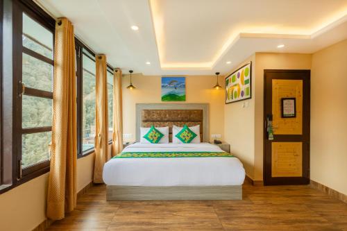 a bedroom with a large white bed and windows at Treebo Lords Garden Glory in Shimla