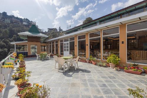 a patio with chairs and tables and a building at Treebo Lords Garden Glory in Shimla