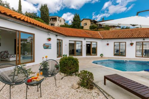 a house with a swimming pool and two chairs at Dream Villa in Tala with Private Pool, Sea & Mountain Views & Garden Retreat in Paphos