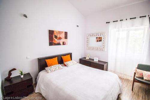 een witte slaapkamer met een groot bed met oranje kussens bij Villa Azul in Boliqueime
