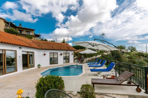 a villa with a swimming pool and lounge chairs at Dream Villa in Tala with Private Pool, Sea & Mountain Views & Garden Retreat in Paphos