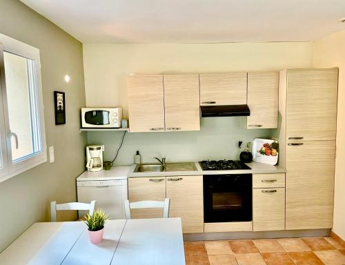 - une cuisine avec des placards en bois, une table et un four micro-ondes dans l'établissement l'Exotica ,au cœur d'une pinède, à Palaja