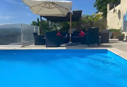 a blue swimming pool with chairs and an umbrella at Belle Maison dans le Beaujolais in Gleizé