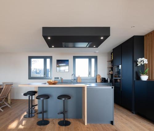 une cuisine avec des placards noirs et un comptoir avec des tabourets dans l'établissement Architect-designed villa with sea view, à Barneville-Carteret