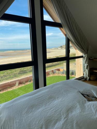 - une chambre avec un lit et une vue sur un champ dans l'établissement Architect-designed villa with sea view, à Barneville-Carteret