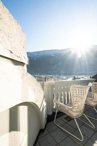 a pair of chairs sitting on a balcony with the sun at Bernina Express Eco Rooms&Breakfast in Tirano