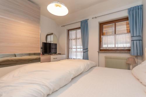 a bedroom with a large white bed and a television at Appartamento Iori in Canazei