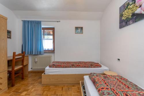 a bedroom with two beds and a table and a desk at Appartamento Iori in Canazei