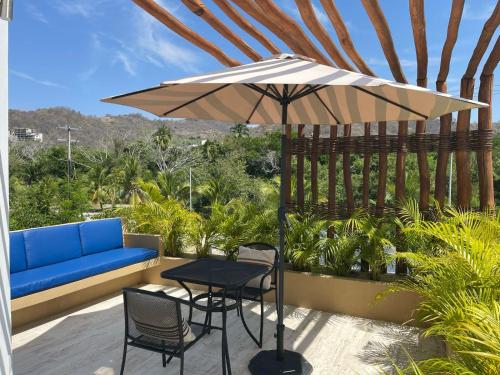 un patio con mesa, sofá y sombrilla en Luana suites- Suite Nikté, en Zihuatanejo