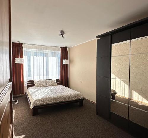a bedroom with a bed and a large window at Evergreen City Apartment in Valmiera