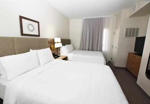 a hotel room with two beds and a television at Staybridge Suites Detroit-Novi by IHG in Novi