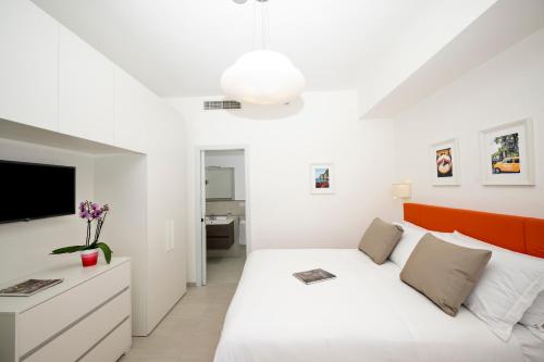 a white bedroom with a bed and a tv at Villa Leonardo in the heart of Positano in Positano
